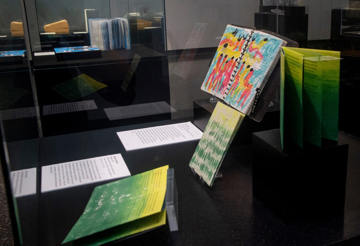 Image depicts brightly-colored, hand-made artists' books in a vitrine.