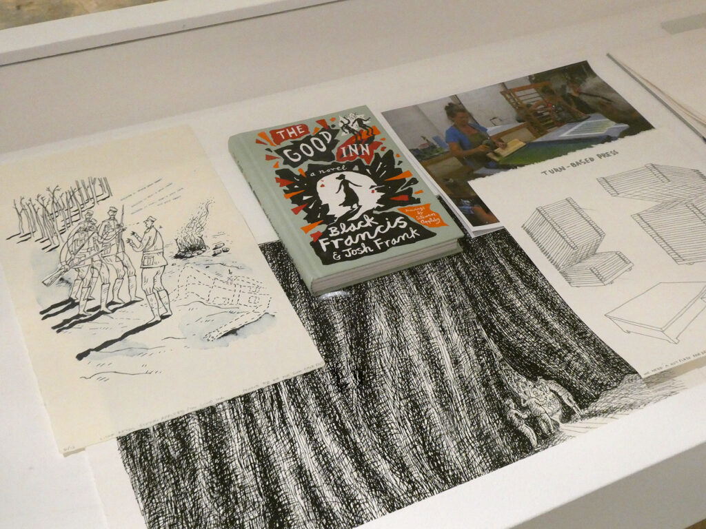 This image depicts the contents of a vitrine; they include an inkjet photo, a harcover book, two screenprints and a pronto-plate lithograph.